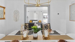 A dining area with a table set for two, featuring a central plant, two candle holders, and a chandelier. - Bohemian Styled Home with Bonus Game Room (Kannapolis)