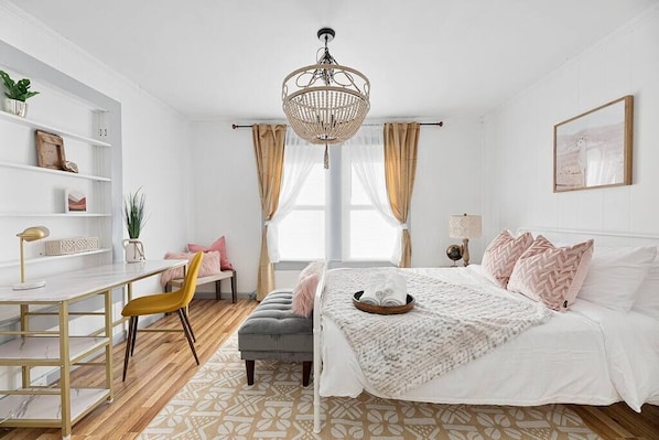 Une chambre à coucher avec un lit, un bureau, une chaise, une bibliothèque et une fenêtre avec des rideaux.