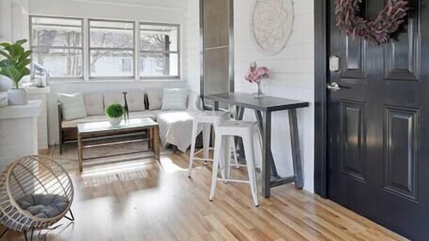 A bright, open-plan living space with a wooden floor, a black door, and a windowed wall. - Bohemian Styled Home with Bonus Game Room (Kannapolis)