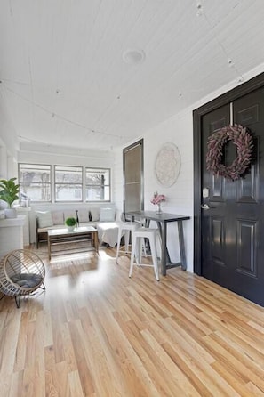 Un espace de vie lumineux et ouvert, avec un plancher en bois, une porte noire et un mur entièrement vitré.