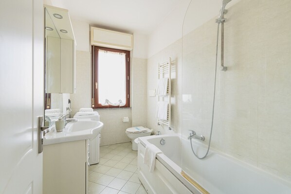 A bathroom with a bathtub, a toilet, a sink, and a window.