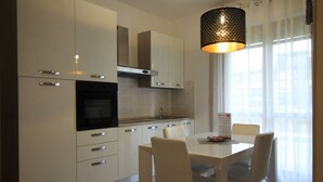 Eine moderne Küche mit weißen Schränken, einem schwarzen Backofen und einem Essbereich mit weißem Tisch und Stühlen.