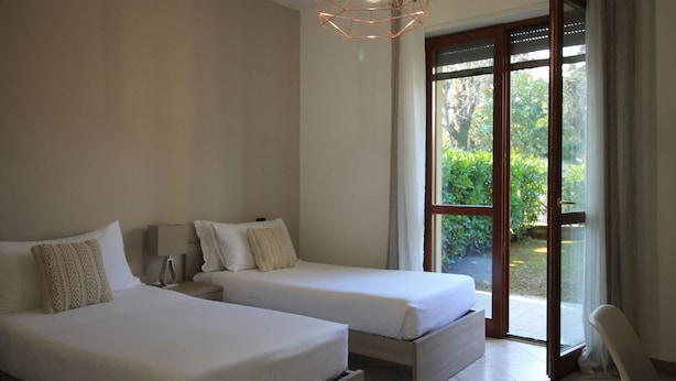 Ein Schlafzimmer mit zwei Betten, einem großen Fenster und Blick auf Grün.