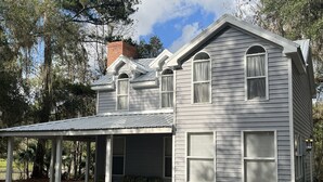 Une maison à deux étages avec un porche couvert et une cheminée.