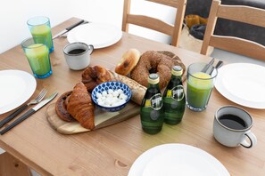 A breakfast table with croissants, bagels, a bowl of eggs, green juice, and coffee. - Elegant 2BD Apartment in Jaffa Area (Tel Aviv)