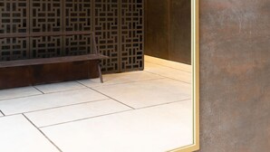 A modern interior with a geometric patterned wall, a bench, and a large mirror reflecting the space. - Elegant 2BD Apartment in Jaffa Area (Tel Aviv)