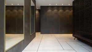 A modern bathroom with dark tiled walls, a large mirror, and a bench. - Elegant 2BD Apartment in Jaffa Area (Tel Aviv)