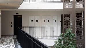 A modern building with a geometric tiled floor, a black railing, and a vertical wooden panel design. - Elegant 2BD Apartment in Jaffa Area (Tel Aviv)