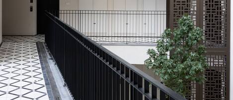 A modern building with a geometric tiled floor, a black railing, and a vertical wooden panel design.