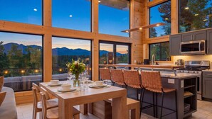 A modern kitchen with large windows, a dining area, and a view of mountains. - Lakefront - Alpine Views - Daily Moose (Black Hawk)
