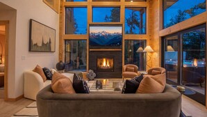 A modern living room with a fireplace, large windows, and a cozy seating area. - Lakefront - Alpine Views - Daily Moose (Black Hawk)