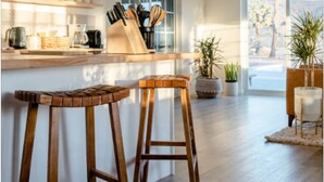 A modern kitchen with wooden stools, a hanging light fixture, and a view of the outdoors. - The Blue Cactus Ranch - Pool and Spa (Joshua Tree)