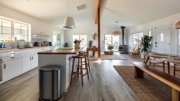 A spacious kitchen with wooden countertops, a central island with stools, and a dining area with a bench and chairs. - The Blue Cactus Ranch - Pool and Spa (Joshua Tree)
