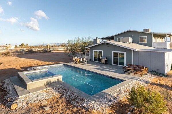Ein modernes Haus mit Swimmingpool, Terrassenmöbeln und Blick auf die Wüstenlandschaft.