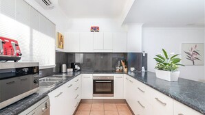 A modern kitchen with white cabinets, a black countertop, and a Bosch oven. - Modern 2 bed townhouse 200 metre from beach - your home away from home (Port Douglas)