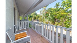 A covered balcony with white railings, a tiled floor, and outdoor furniture. - Modern 2 bed townhouse 200 metre from beach - your home away from home (Port Douglas)
