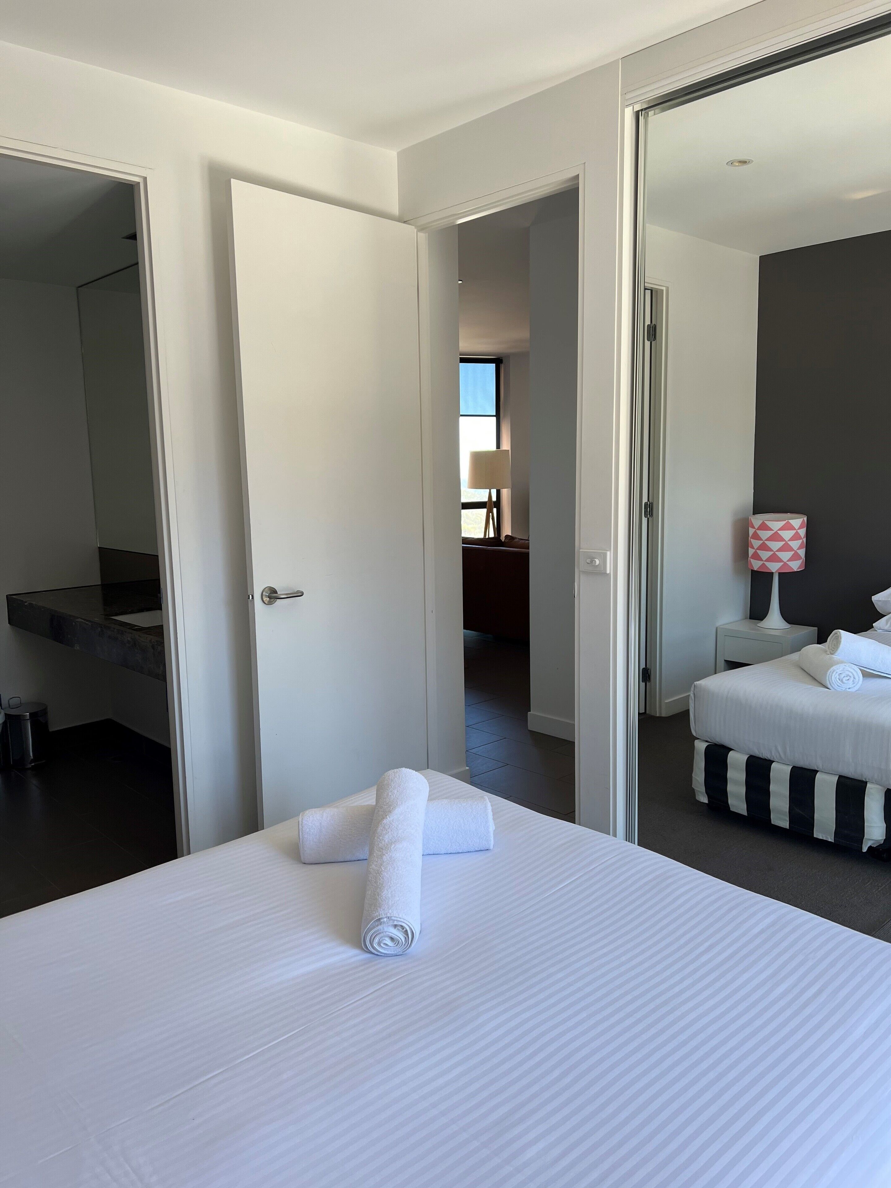 A hotel room with a bed, a bedside table with a lamp, and a mirror.