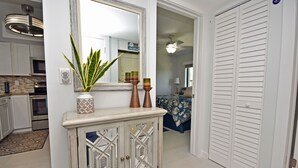 Un couloir agrémenté d’une vitrine décorative, d’un miroir et d’une plante en pot.