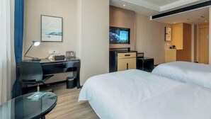 Habitación de hotel con dos camas, un escritorio con silla, televisión y una mesita.