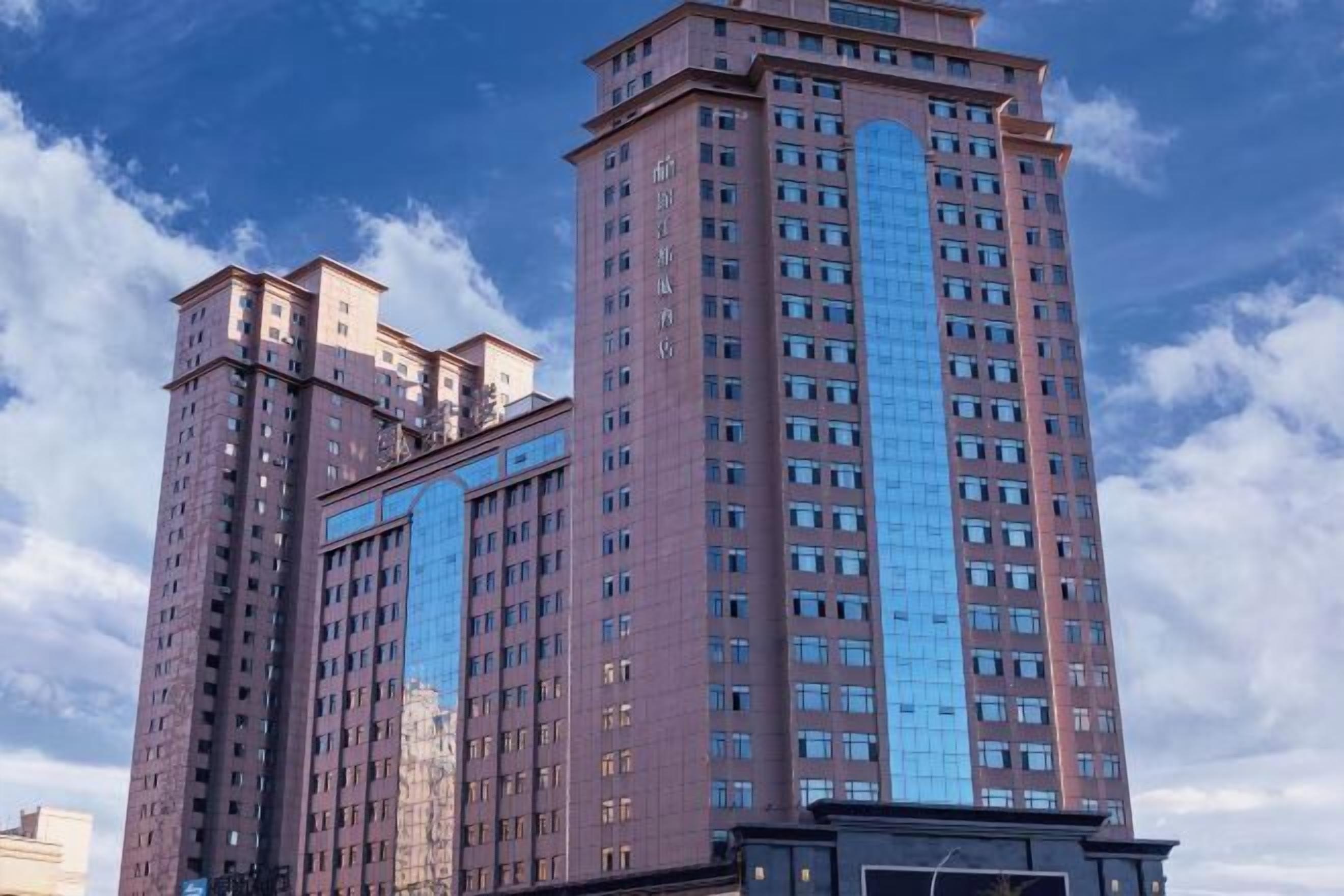 A high-rise building with multiple floors, large windows, and a prominent central glass facade.