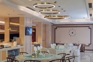 Un comedor moderno con mesas redondas, sillas y un gran reloj de pared.