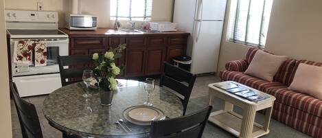 A compact kitchen with a dining area, a refrigerator, a microwave, and a stove.