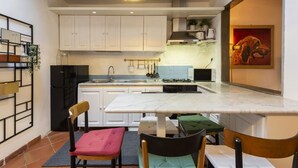 A compact kitchen with white cabinets, a marble countertop, and a hanging light fixture.