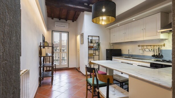 A kitchen with a large island, white cabinets, and a hanging light fixture.
