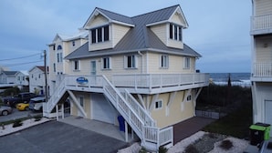 A two-story building with a balcony and a staircase leading to the entrance. - Beach Front with Charm and Luxury. 2 person Hot Tub on Deck. Beautiful Loft! (North Topsail Beach)