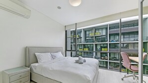 Une chambre moderne avec une grande fenêtre, un lit, un bureau et une chaise.