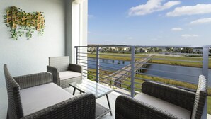 Ein Balkon mit Korbmöbeln und Blick auf ein Gewässer und eine entfernte Landschaft.