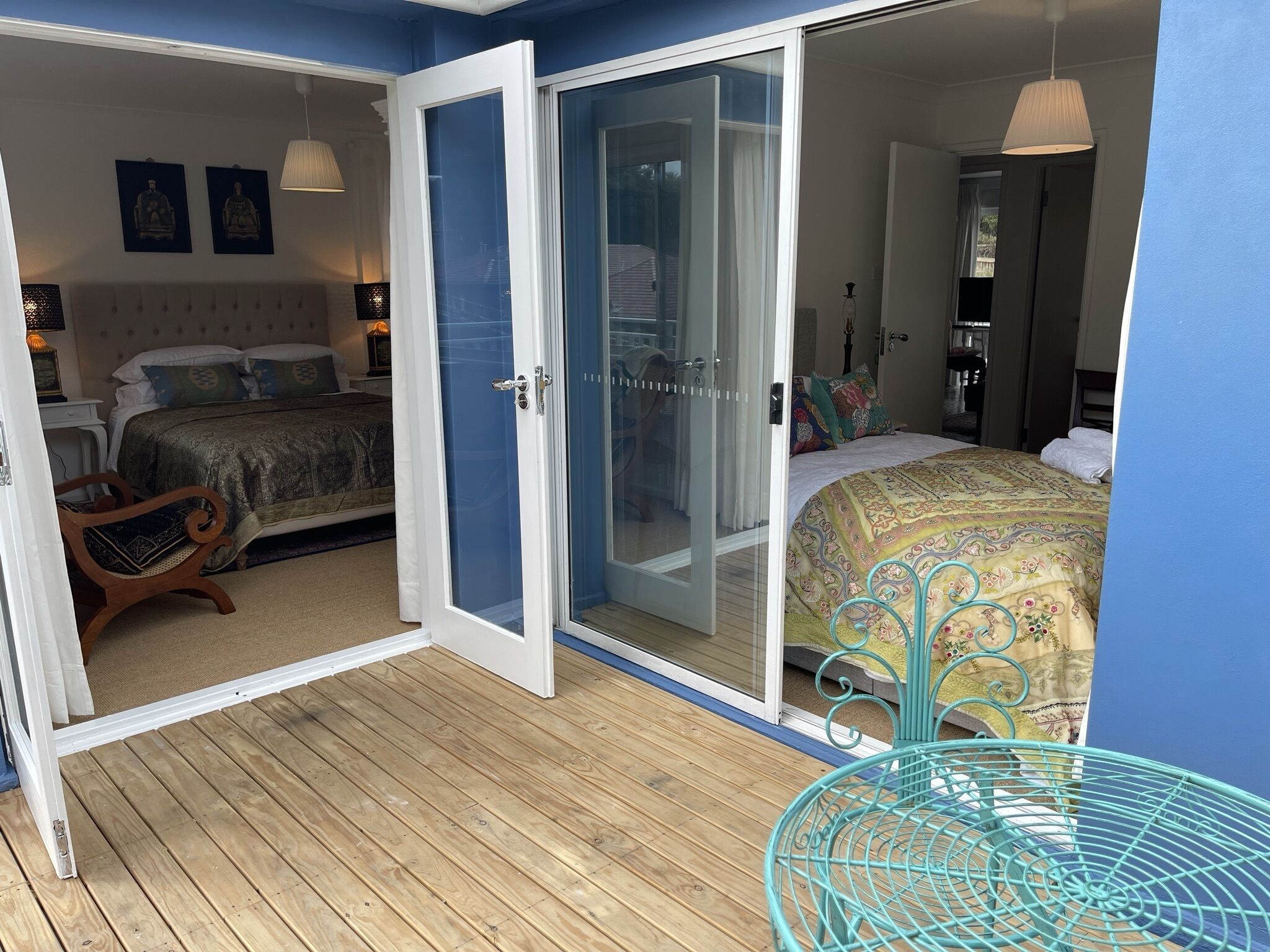 A bedroom with a large bed, a wooden floor, and a sliding glass door leading to a balcony.