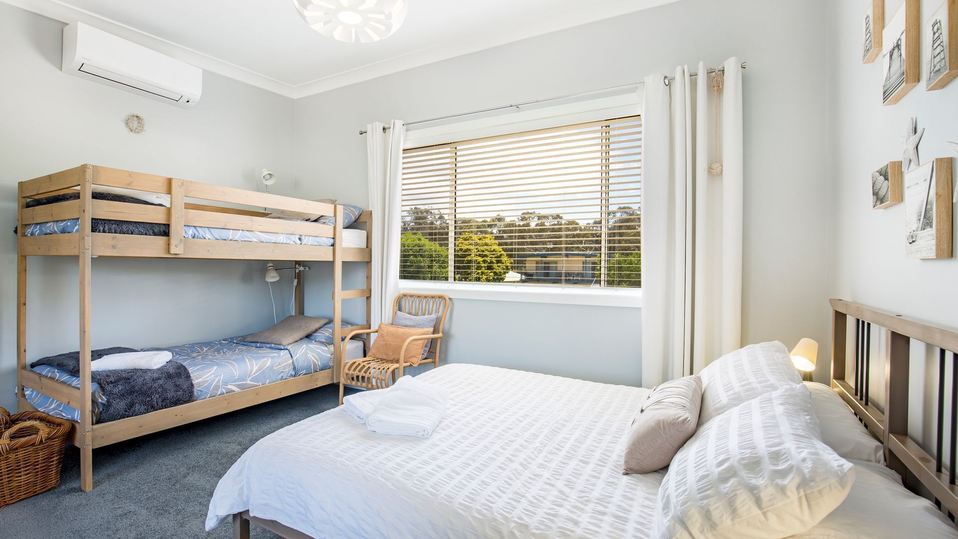 Un dormitorio con una litera, una cama individual, una ventana con persianas y vistas al exterior.