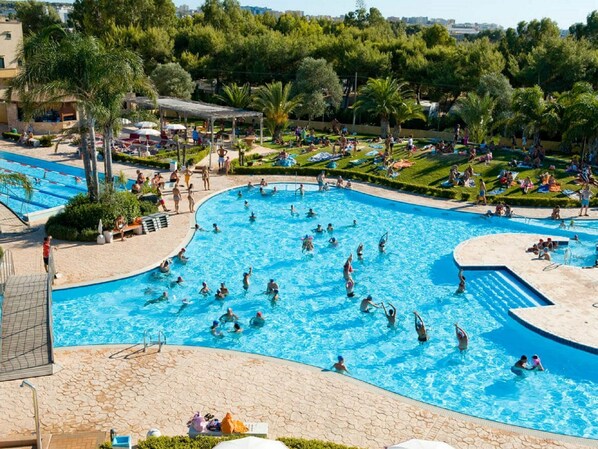 Une grande piscine extérieure entourée d’espaces de détente et de verdure.