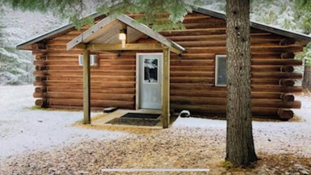 A log cabin with a front porch, a door, and a small window. - Rustic log cabin (Naples)