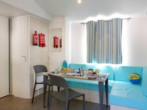A room with a table set for breakfast, a sofa, and a window with striped curtains.