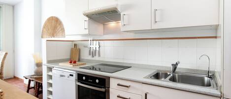 A modern kitchen with white cabinetry, a stainless steel sink, and a built-in oven.