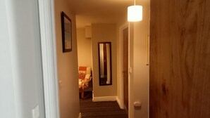 En hall med ett mattbeklätt golv, en trädörr och en lampa.