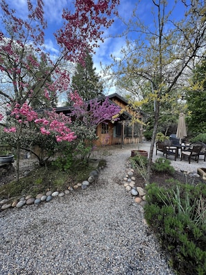 Une cabane en bois avec un chemin de gravier menant à un espace patio.