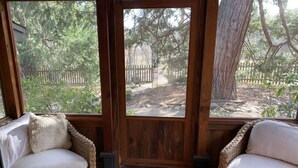 A covered porch with wicker furniture and a view of a fenced garden area. - Starview Ranch: 3 homes w/ 7 bdrms, pool, sauna, spa & gym on 50 beautiful acres (Miramonte)