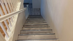 A wooden staircase with white railings leading to a room with a blue door. - Nice remodeled House for rent in West side of Palmdale (Palmdale)