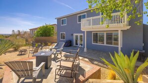 A two-story house with a balcony, outdoor seating area with chairs and a table, and a garden with plants. - Nice remodeled House for rent in West side of Palmdale (Palmdale)