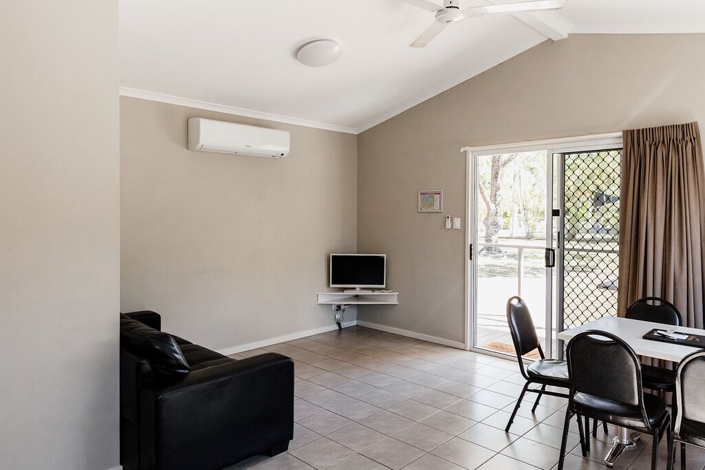Un salon moderne doté d’un téléviseur à écran plat, d’un ventilateur de plafond et d’un coin repas avec une table et des chaises.