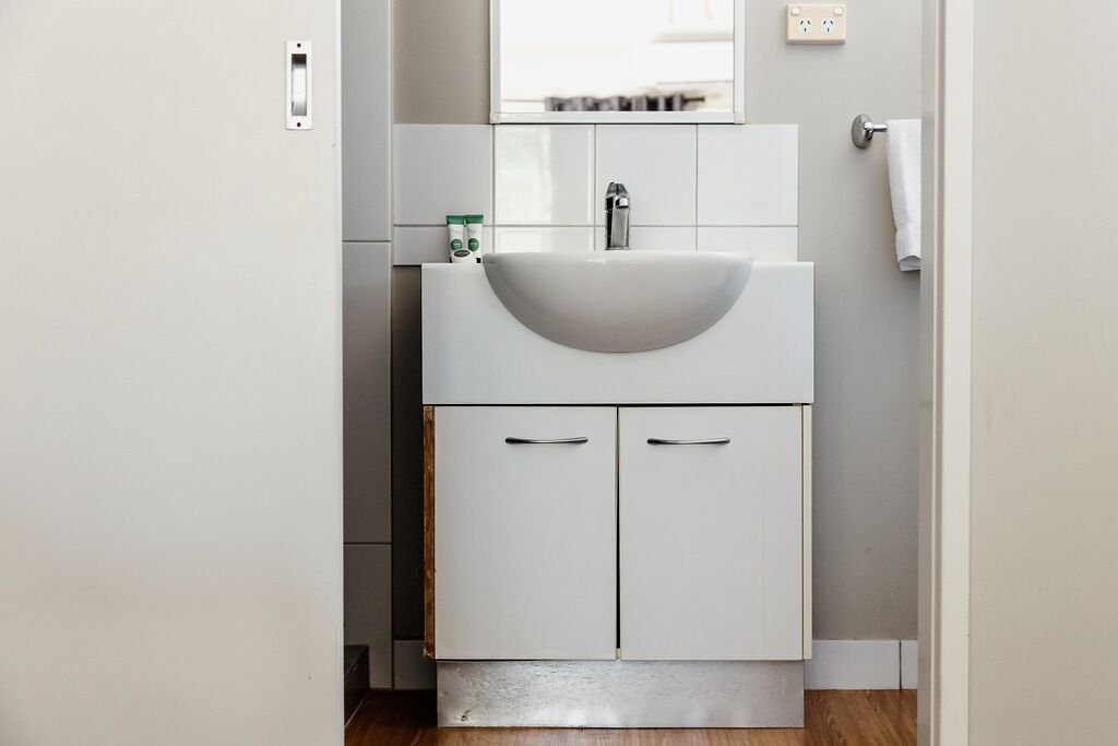 A bathroom with a white sink, two cabinets, and a mirror above the sink.