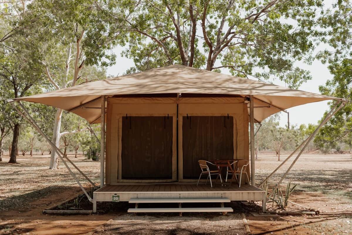 Une tente composée d’une seule pièce, avec un banc en bois et deux chaises à l’extérieur.