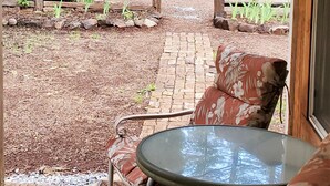 A covered patio with a table and chairs, a wooden fence, and a view of a wooded area. - Cottage #2 with a Lake and Creek, 15 mi to Lassen NP (Shingletown)