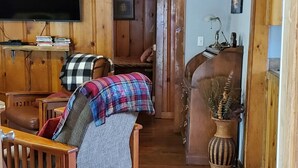 A cabin interior with a bed, a television, a desk, and a welcome sign. - Cottage #2 with a Lake and Creek, 15 mi to Lassen NP (Shingletown)
