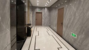 A modern hallway with marble walls and a geometric patterned floor.