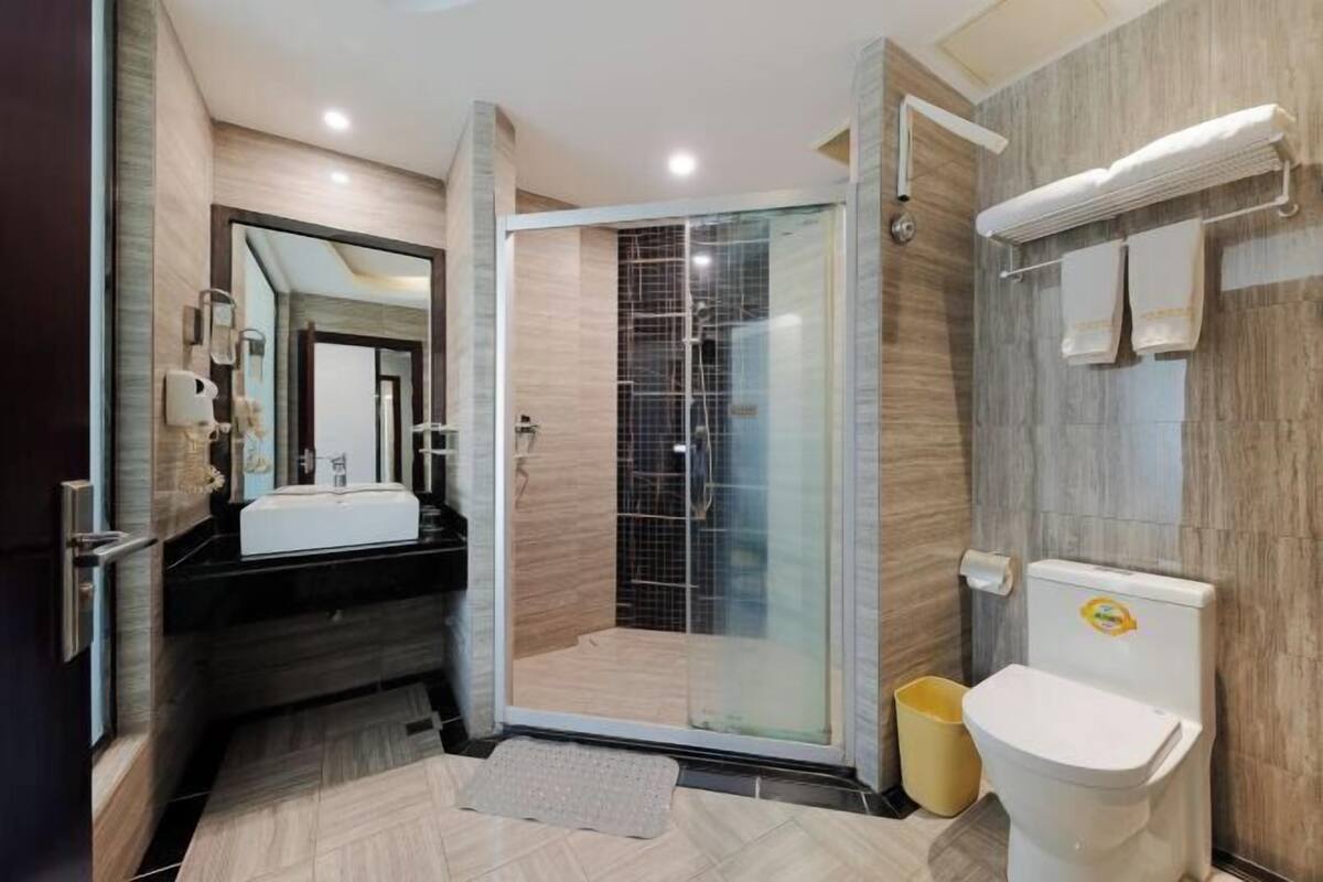 A modern bathroom with a glass-enclosed shower, a sink, and a toilet.