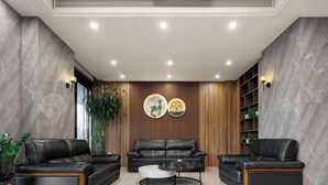 A modern living room with leather sofas, a round coffee table, and a wooden wall panel.